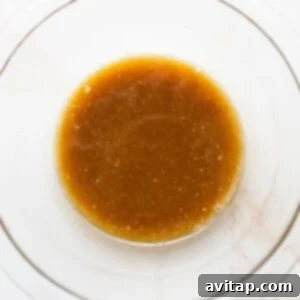 A bowl of marinade, a mix of maple syrup, soy sauce, and Worcestershire sauce, ready to be brushed on the salmon.