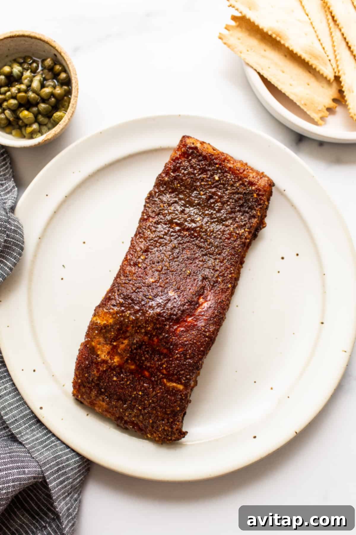 A pristine smoked salmon fillet, perfectly cooked and resting on a plate, showcasing its golden exterior and tender flakiness, ready to be enjoyed.