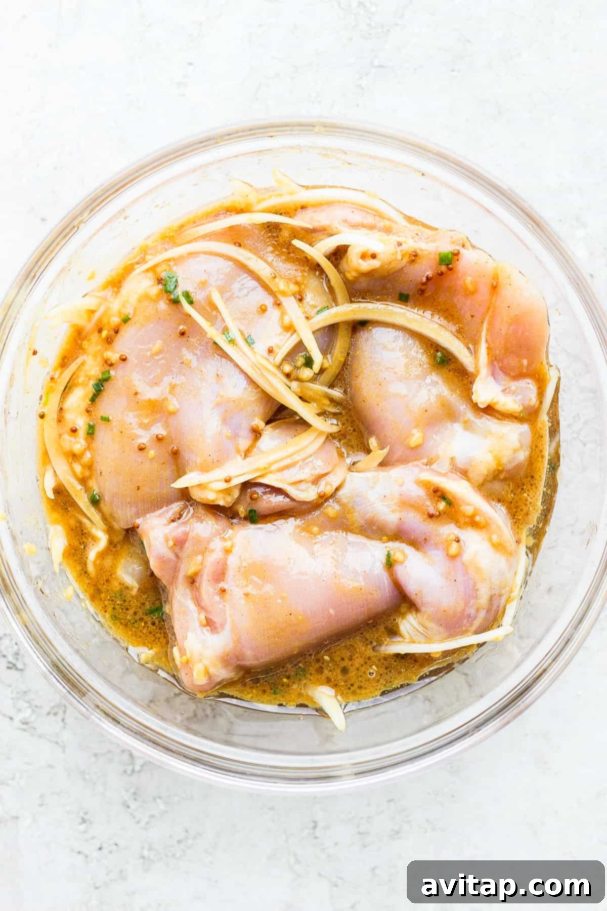 Flavorful Chicken Thighs Made Easy 2 Boneless chicken thighs soaking in a bowl of rich honey mustard marinade.