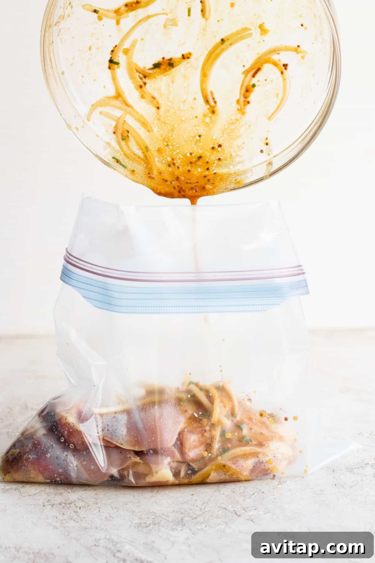 In less than 5 minutes you can whip up a delicious honey mustard chicken thighs marinade that will infuse your chicken thighs with mustard, honey and a hint of lemon! Honey mustard marinade being poured over chicken thighs in a gallon-size bag.
