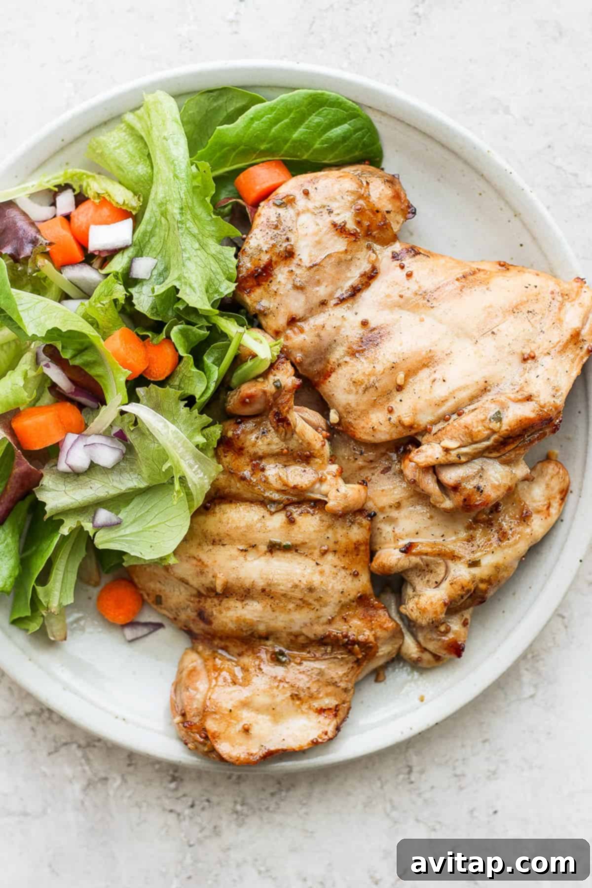In less than 5 minutes you can whip up a delicious honey mustard chicken thighs marinade that will infuse your chicken thighs with mustard, honey and a hint of lemon! Cooked chicken thighs served on a plate with a fresh green salad.