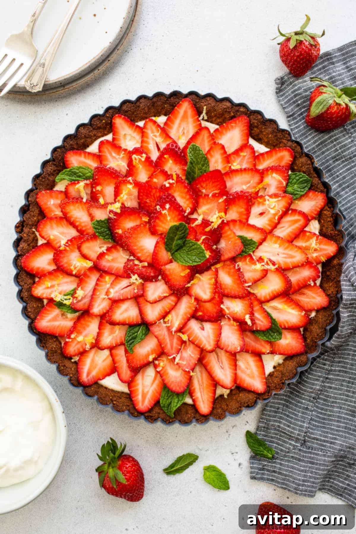A slice of strawberry tart on a small white plate, accompanied by a cup of hot coffee, suggesting a perfect dessert pairing.