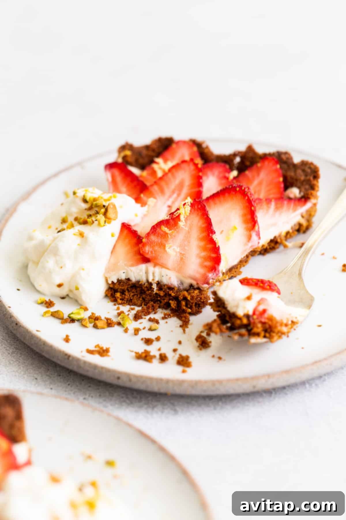 A large, perfectly baked strawberry tart with an intricate strawberry rose pattern on top, garnished with mint, ready for slicing and serving.