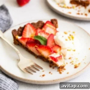 A slice of strawberry pie with whipped cream and a fork, highlighting the delicious layers of the tart.