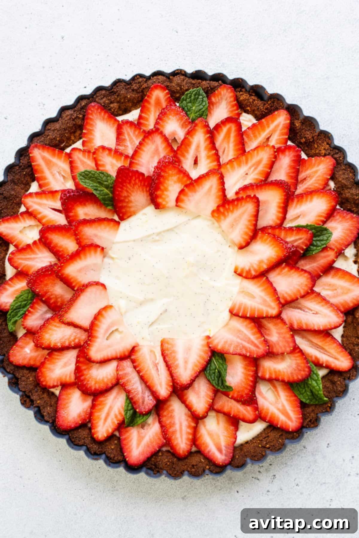 A serving of strawberry tart on a white plate with a fork, elegantly presented and ready to be enjoyed.