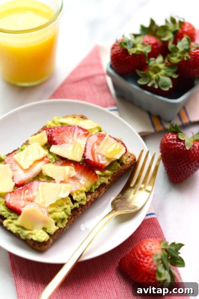 Gourmet toast with fresh strawberries, creamy avocado, and sharp white cheddar slices.