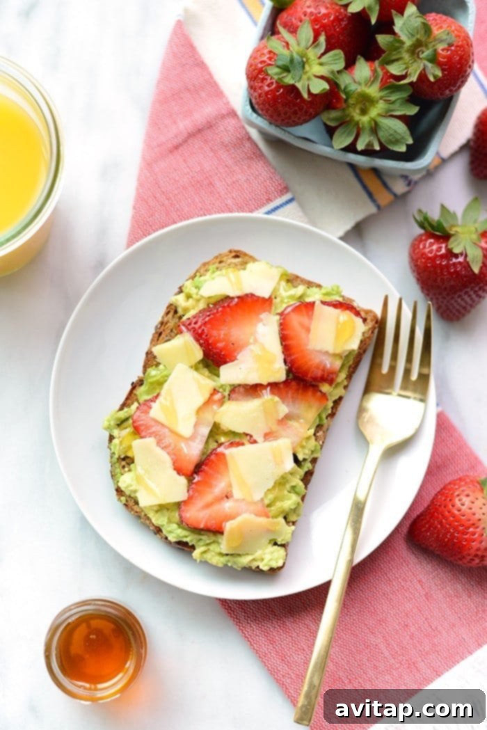 Close-up of strawberry, avocado, and white cheddar toast components on a cutting board.