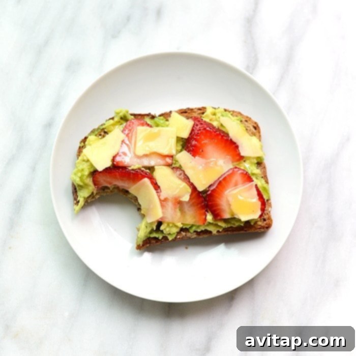 A slice of strawberry, avocado, and white cheddar toast on a plate, ready to be enjoyed.
