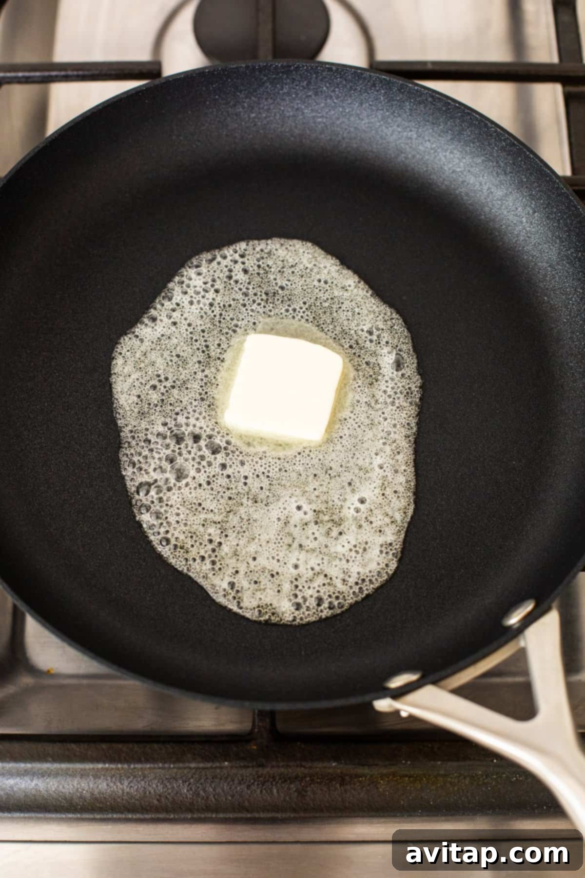 Golden butter melting and sizzling gently in a preheated non-stick skillet, preparing the perfect surface for frying eggs.