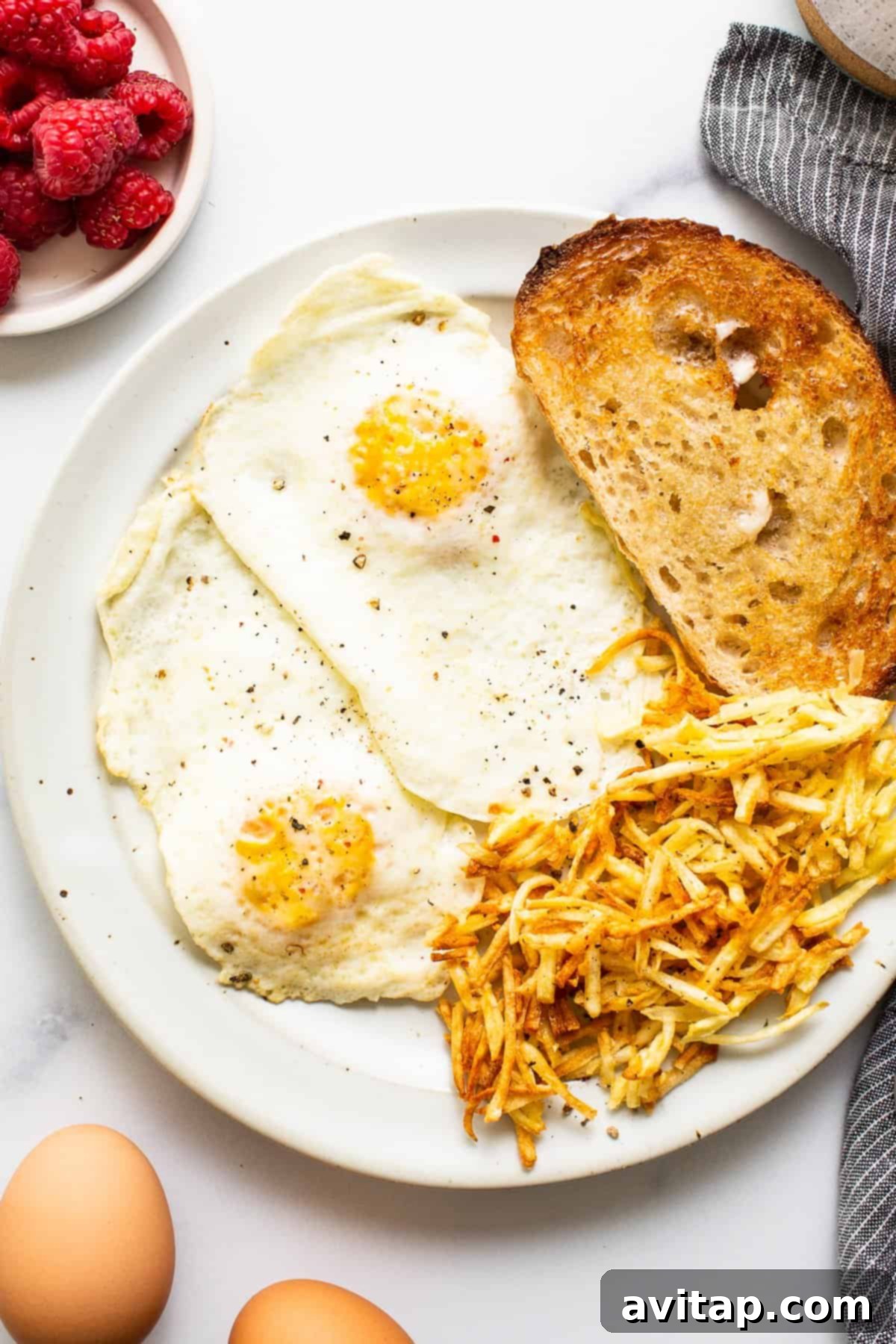 Two perfectly cooked over medium eggs, seasoned with salt and pepper, served with crispy toast on a white plate, highlighting their jammy yolks and firm whites.