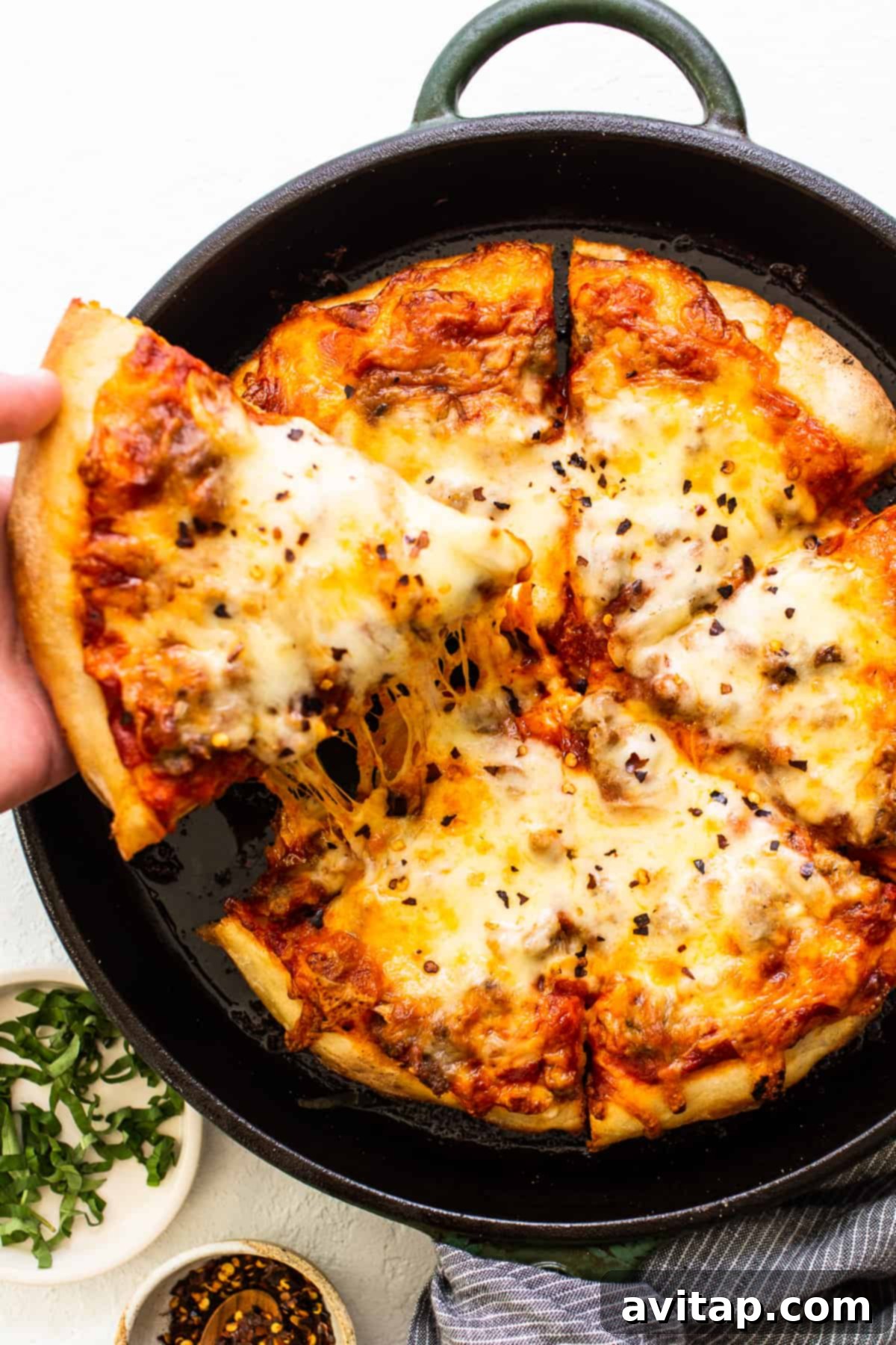 Delicious cast iron pizza with golden, crispy crust and melted cheese, garnished with fresh basil.