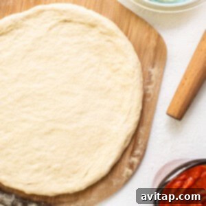 Rolled out pizza dough on a floured surface, ready for cooking.