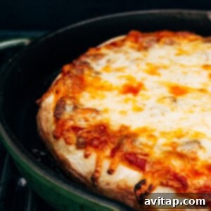 Cast iron pizza cooking on a covered grill, cheese bubbling.