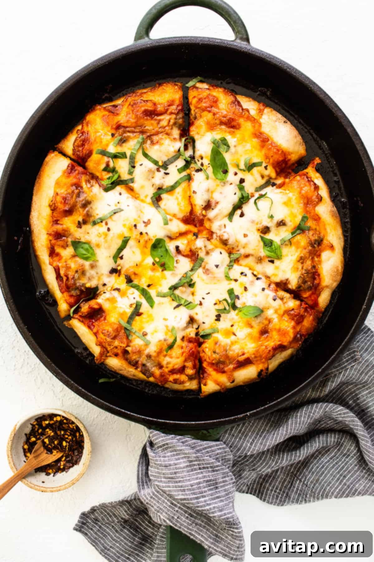 Freshly baked cast iron pizza adorned with vibrant green basil leaves, ready to be served.