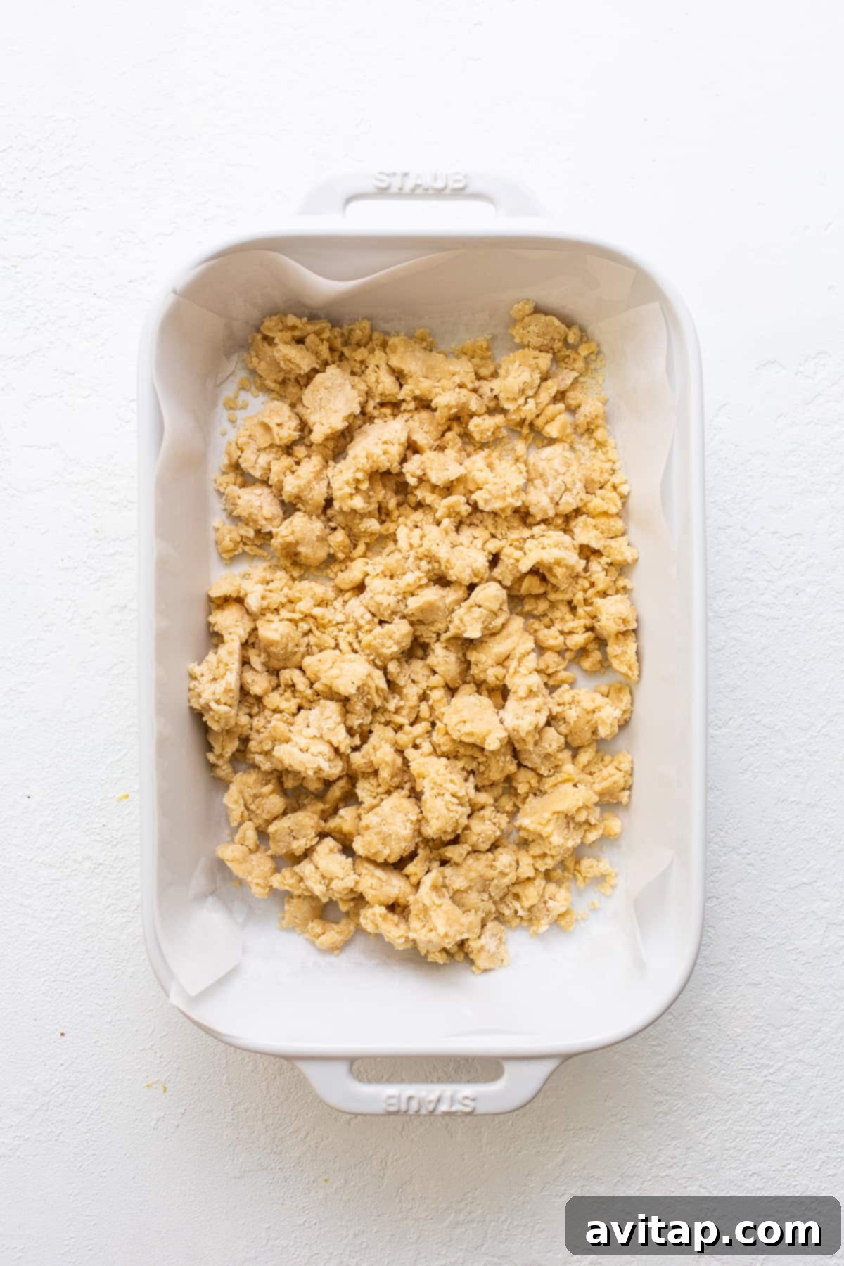 Buttery shortbread crust firmly pressed into a baking pan, ready for the oven.