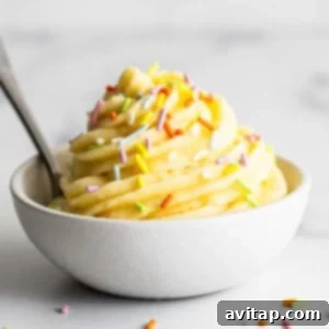 A beautifully swirled bowl of Dole Whip, garnished with colorful sprinkles and a spoon, ready to be enjoyed as a refreshing treat.
