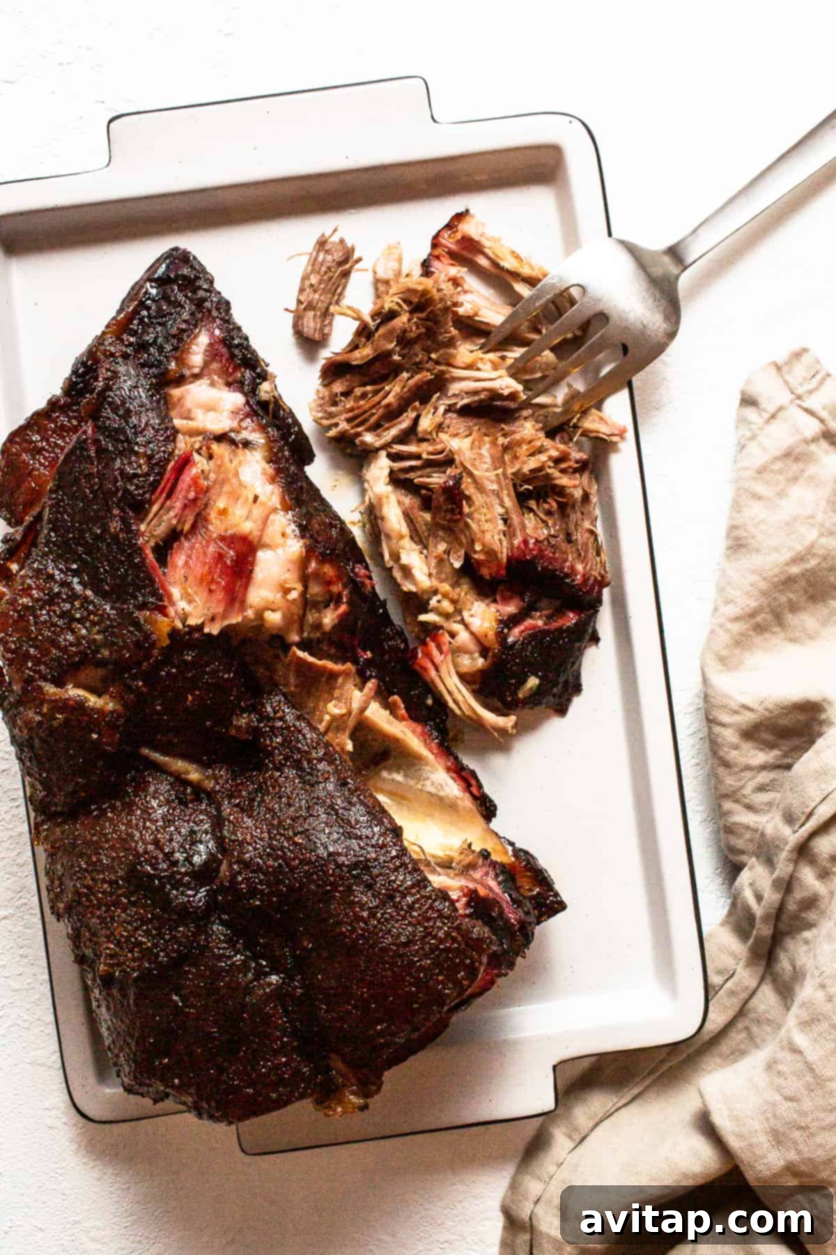 Slow-Smoked Pulled Pork Tacos 2 A perfectly smoked pork shoulder resting on a tray, showcasing its tender texture and delicious crust, ready to be pulled for tacos.