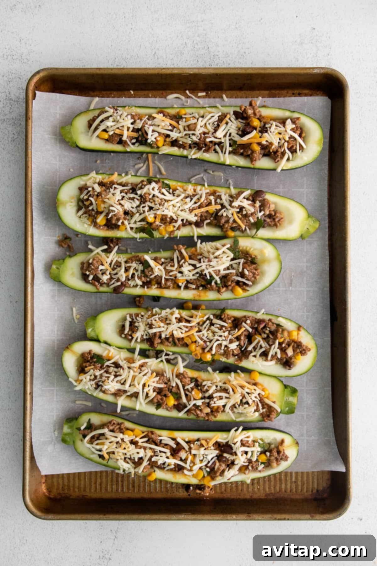 Stuffed zucchini boats arranged neatly on a baking sheet, golden and bubbly after baking.