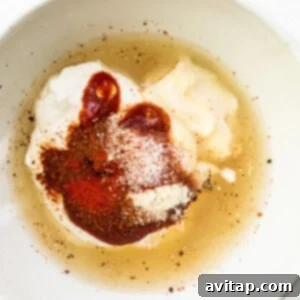 A bowl of soup with spices and sour cream.