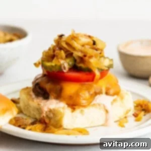 A beautifully presented homemade burger with onions and tomatoes on a plate, captured from an appealing angle, inviting diners to savor its fresh ingredients.
