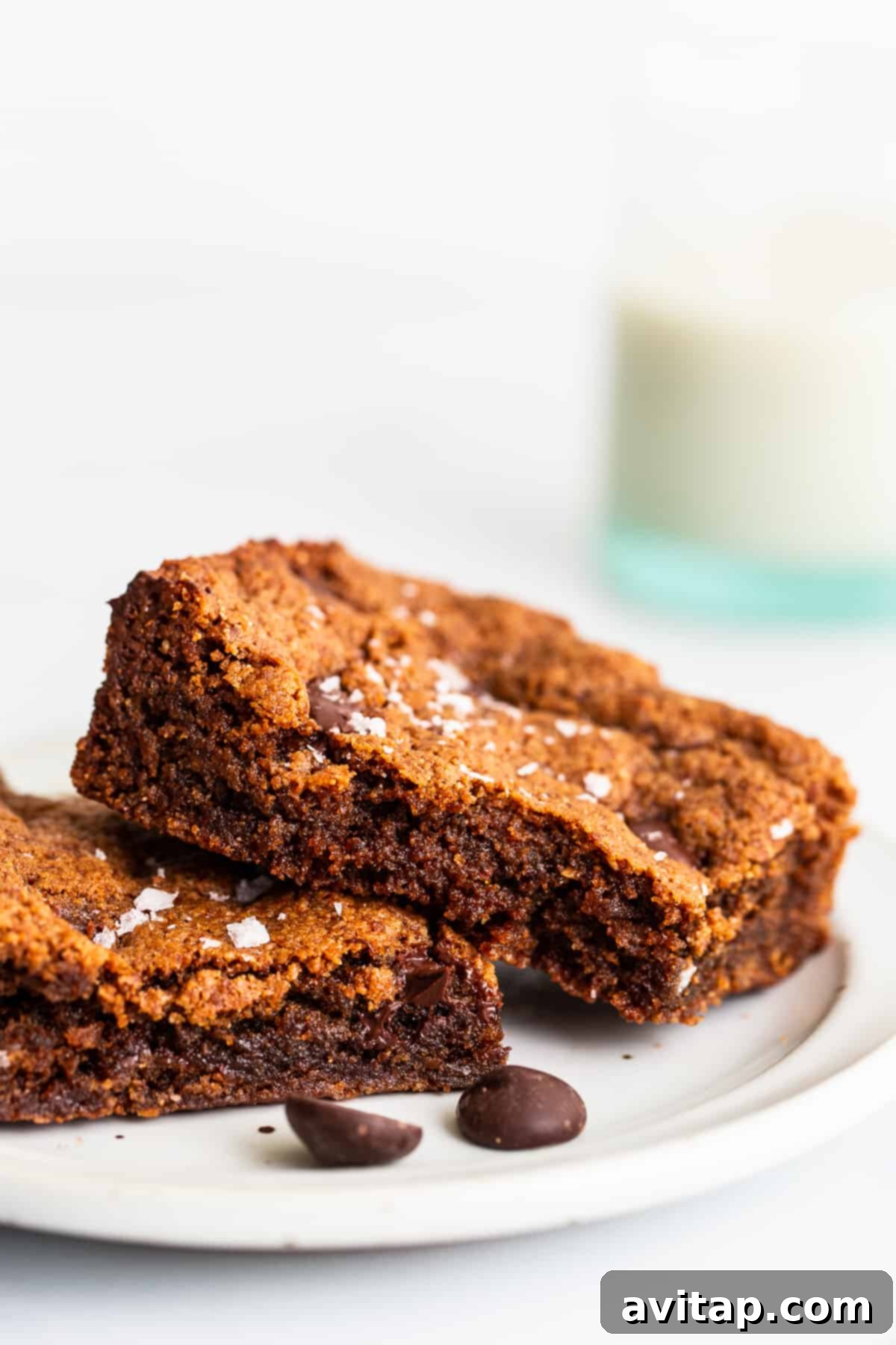 A single flourless almond butter chocolate chip cookie bar served on a white plate, highlighting its rich texture and chocolate chips.