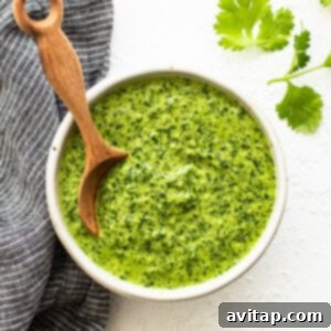 A bowl of vibrant green sauce with a wooden spoon for serving.