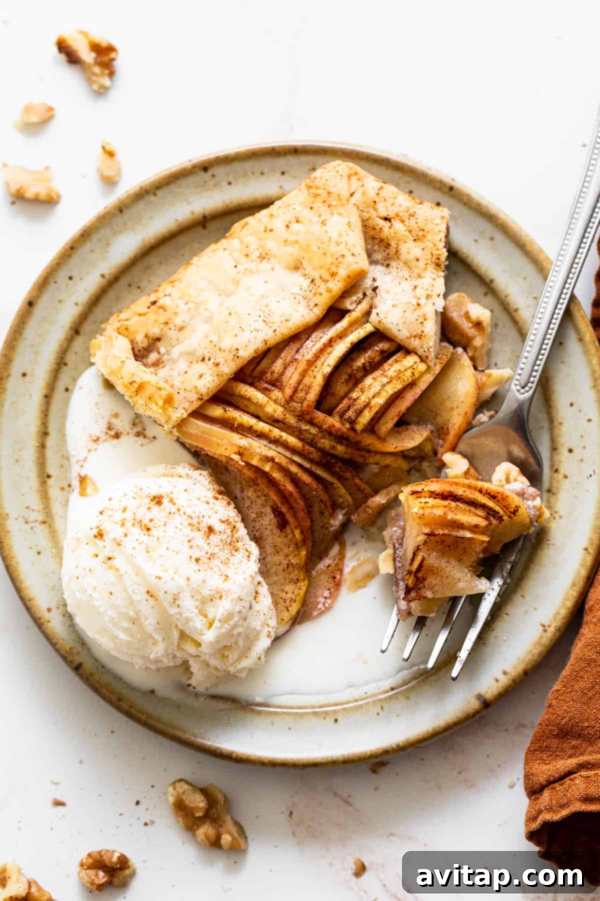 A beautifully baked and sliced brown butter apple galette, showcasing its golden-brown crust and perfectly tender apple filling, resting on a wooden board.