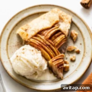 A perfectly baked slice of brown butter apple galette on a white plate, showcasing the golden crust and tender apple filling.