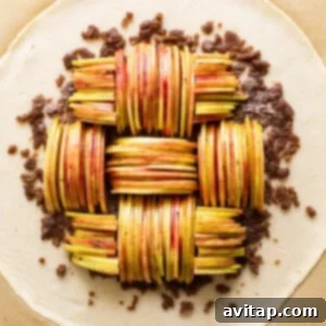 A pie crust with a layer of walnut mixture, topped with artfully arranged apple slices.