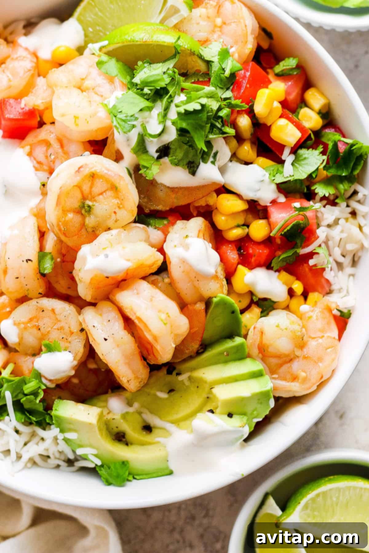 A beautifully assembled cilantro lime shrimp bowl showcasing perfectly cooked shrimp, fluffy rice, creamy avocado, and a generous drizzle of zesty crema, ready to be savored.