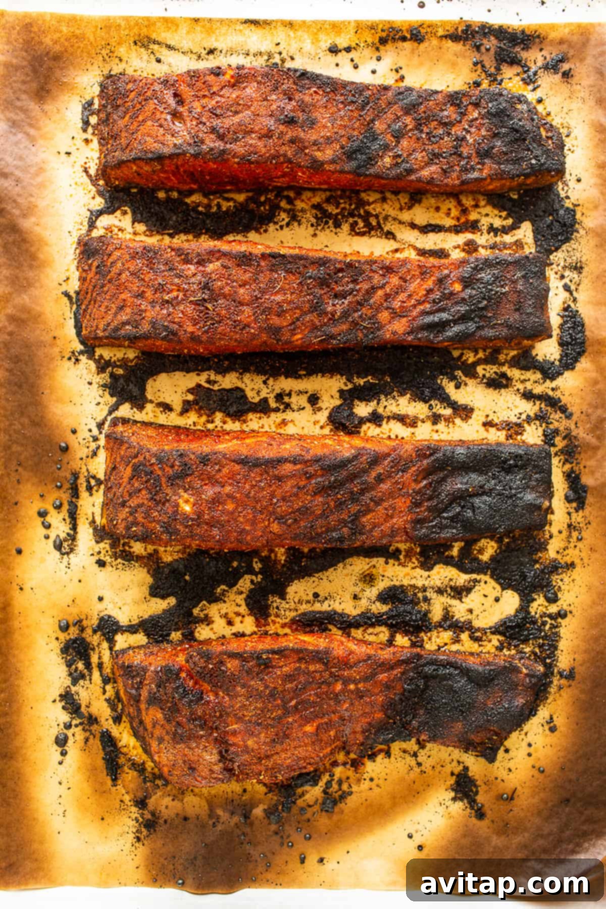 Close-up of freshly broiled blackened salmon, showcasing its crispy spice crust and tender interior, inviting a delicious bite.