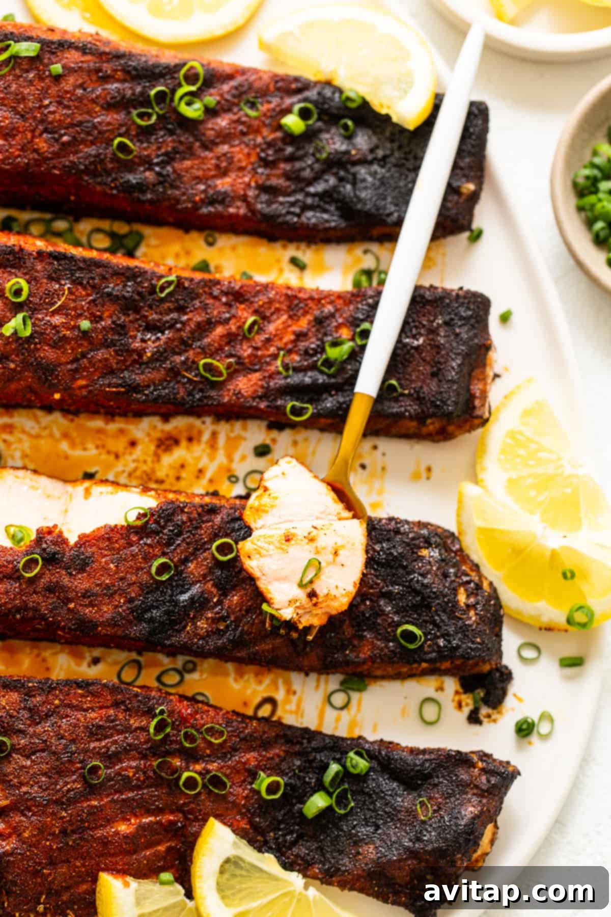 Served blackened salmon garnished with fresh green onion and bright lemon slices, highlighting its vibrant presentation.