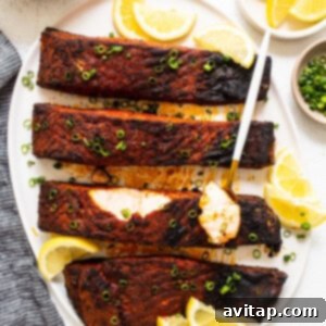 Blackened salmon garnished with fresh lemon juice and herbs.