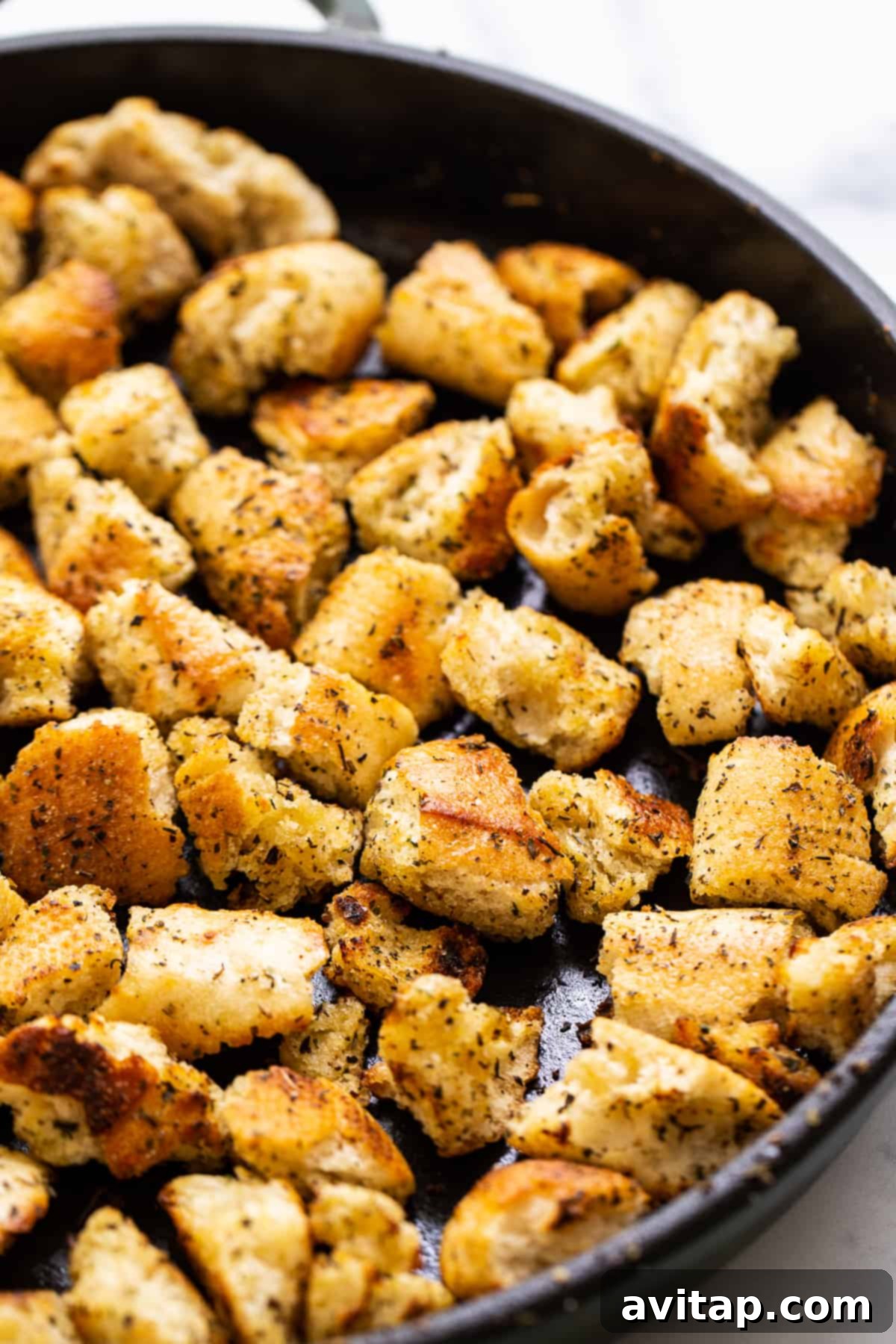 Golden brown homemade croutons in a cast iron skillet, perfectly seasoned and ready to serve, showcasing their irresistible crunchy-chewy texture.