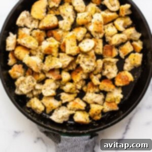 Homemade croutons being pan-fried in a cast iron skillet, turning golden brown and perfectly crispy.