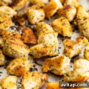 Freshly pan-fried homemade croutons cooling on a baking sheet, showcasing their appealing golden color and tempting texture.