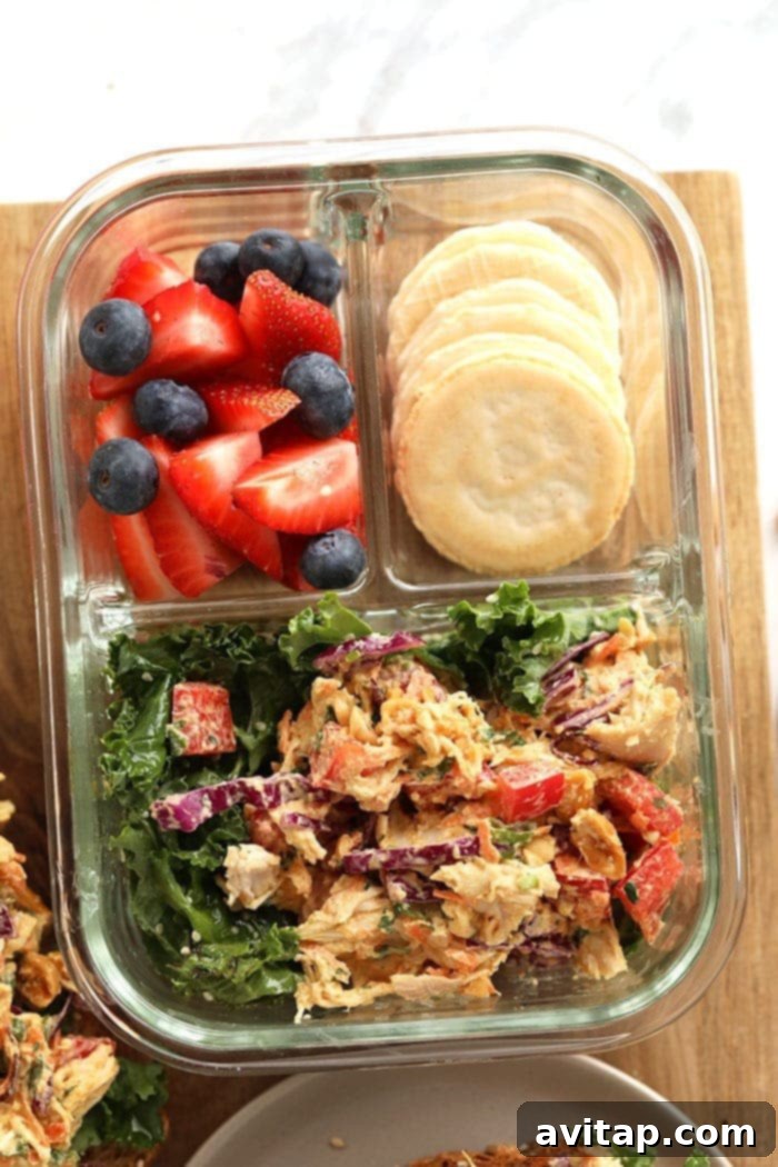 Thai Peanut Chicken Salad neatly arranged in a clear glass meal prep container, accompanied by fresh berries and whole-grain crackers, showcasing a balanced and healthy lunch option.