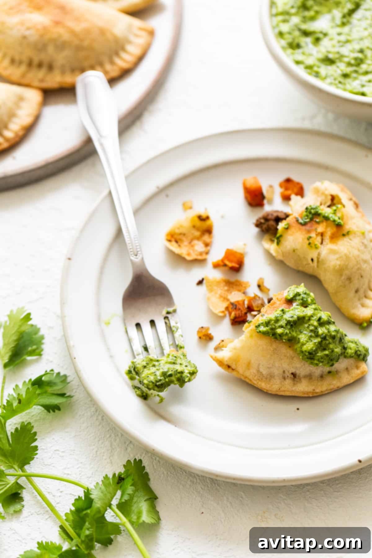Crispy sweet potato ground beef empanadas served with a side of fresh green herb sauce.