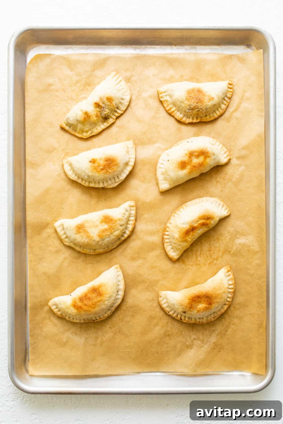 A platter of freshly baked sweet potato ground beef empanadas, golden brown and ready to be enjoyed.