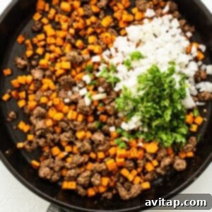 Ground beef and spices cooking in a skillet for empanada filling.