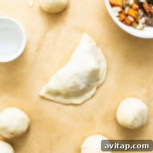 Empanada dough being rolled out and filled, prior to baking.