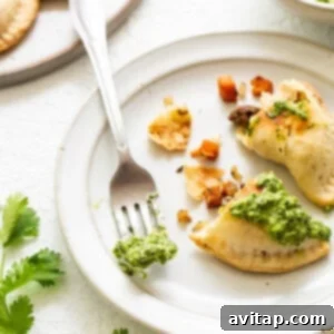 Freshly cooked empanadas garnished with green sauce on a white plate.