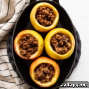 Stuffed apples in a cast iron skillet, covered with foil for final baking.