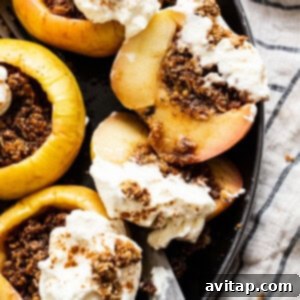 Stuffed apples in a skillet with whipped cream and granola, ready to be enjoyed.