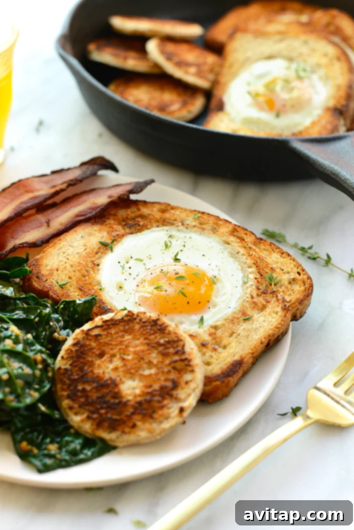 Egg in a hole on a plate, served alongside crispy bacon for a complete breakfast.
