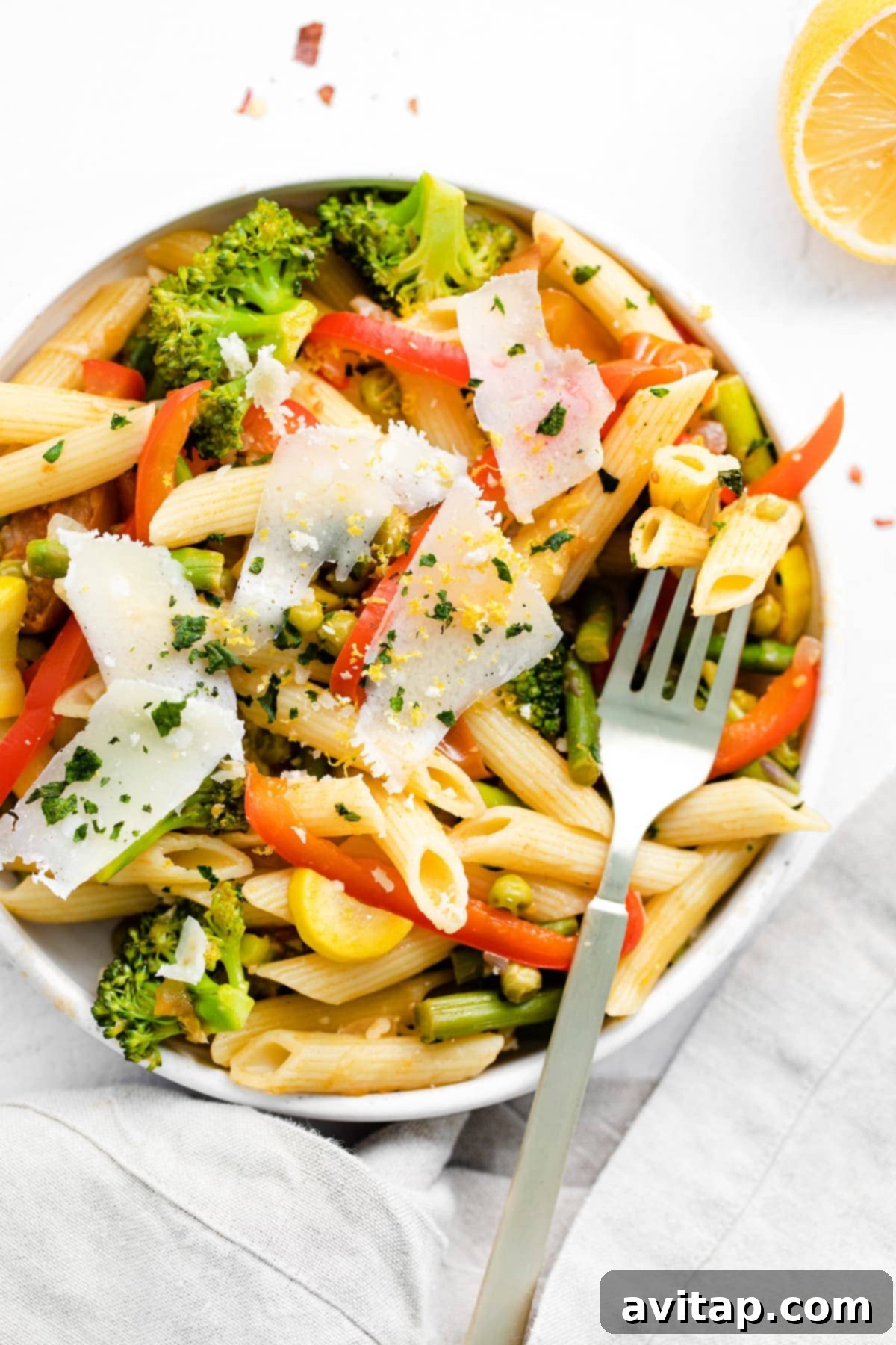 pasta primavera in a bowl topped with parmesan cheese and fresh basil