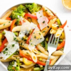 A bowl of pasta primavera with vegetables and Parmesan cheese.