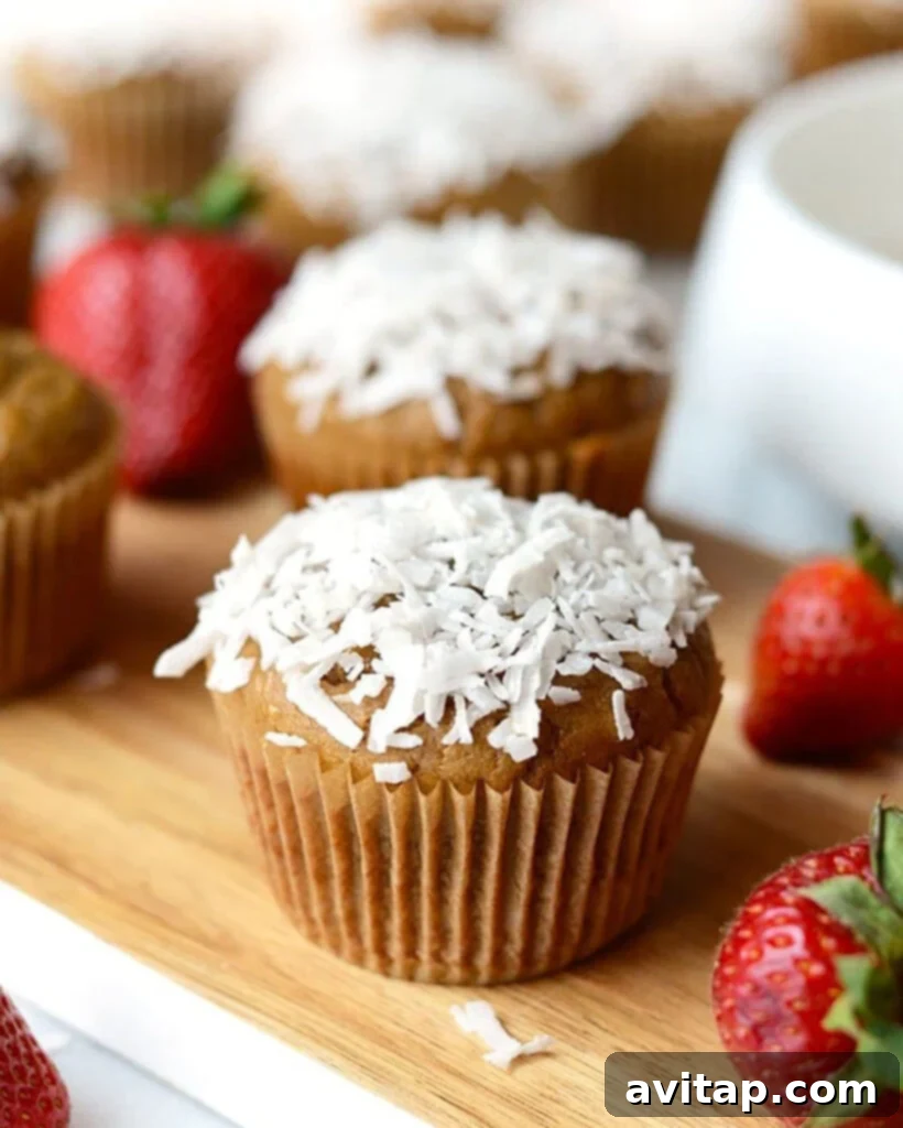 Whirlwind Strawberry Banana Muffins 4 Delicious coconut cupcakes with fresh strawberries on a rustic wooden cutting board, ideal for a Blender Muffins gathering or a healthy snack.