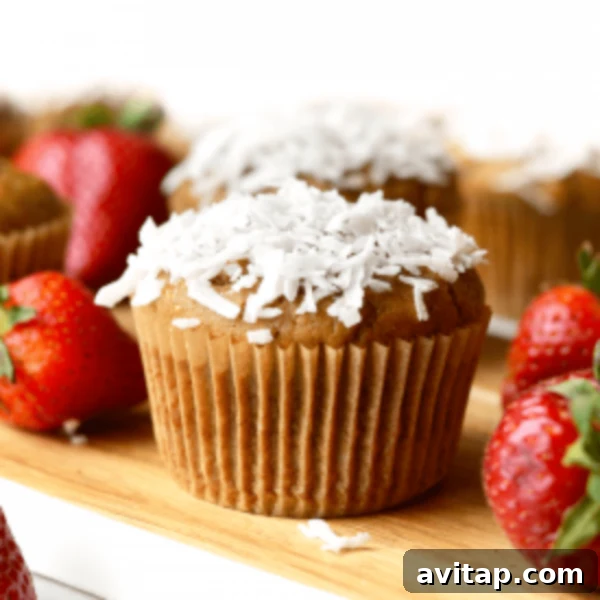 A tray of muffins with strawberries and coconut flakes.