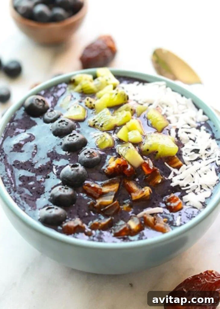 A delicious Blueberry Smoothie Bowl topped with fresh kiwi slices, crunchy granola, and juicy blueberries, ready to be enjoyed.